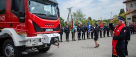 Na zdjęciu widoczny Małopolski Kapelan Strażaków podczas święcenia czerwonego samochodu pożarniczego po jego prawej stronie poczty sztandarowe z OSP z powiatu gorlickiego. 