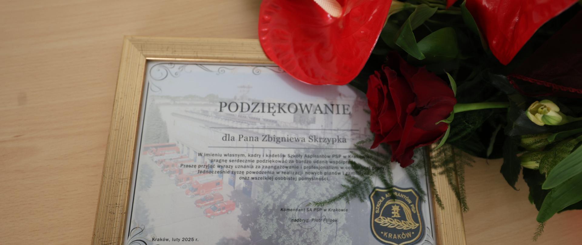 Beżowa ławka, na niej pamiątkowy dyplom dla odchodzącego na emeryturę pracownika oraz bukiet kwiatów. 