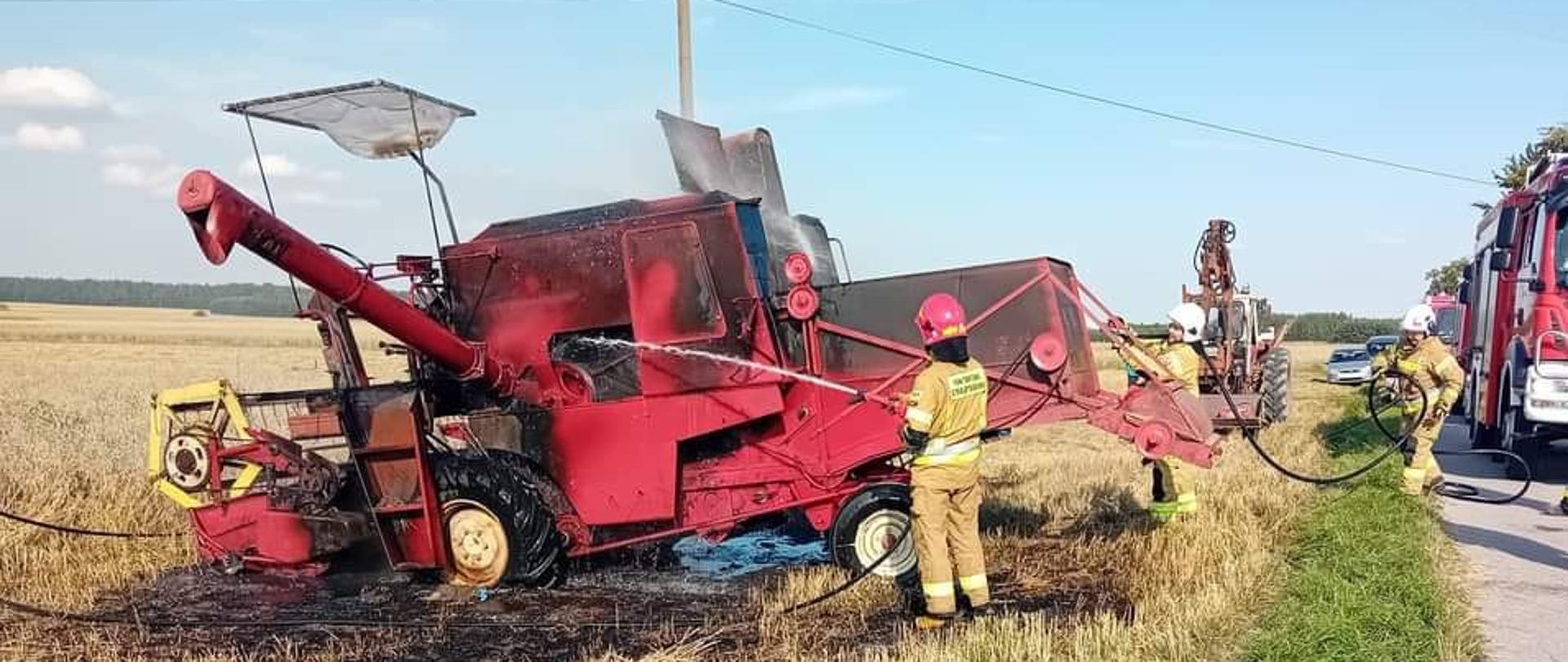 Na zdjęciu widzimy strażaków gaszących pożar kombajnu zbożowego przy użyciu wody z linii gaśniczej.