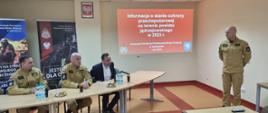 Przy stole prezydialnym widać od lewej zastępcę komendanta powiatowego PSP w Jędrzejowie bryg. Tomasza Szymańskiego, zastępcę świętokrzyskiego komendanta wojewódzkiego PSP w Kielcach st. bryg. Grzegorza Rajcę, starostę jędrzejowskiego. Prezentację przedstawia komendant powiatowy PSP w Jędrzejowie mł. bryg. Mariusz Stolarczyk.