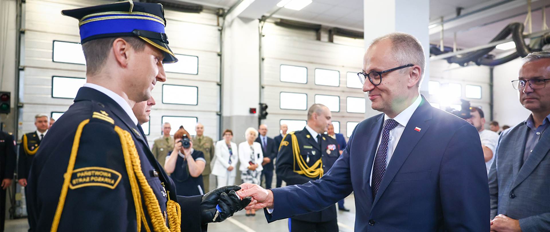 Na zdjęciu wiceminister Błażej Poboży wręczający strażakowi klucze do nowego samochodu ratowniczo-gaśniczego.