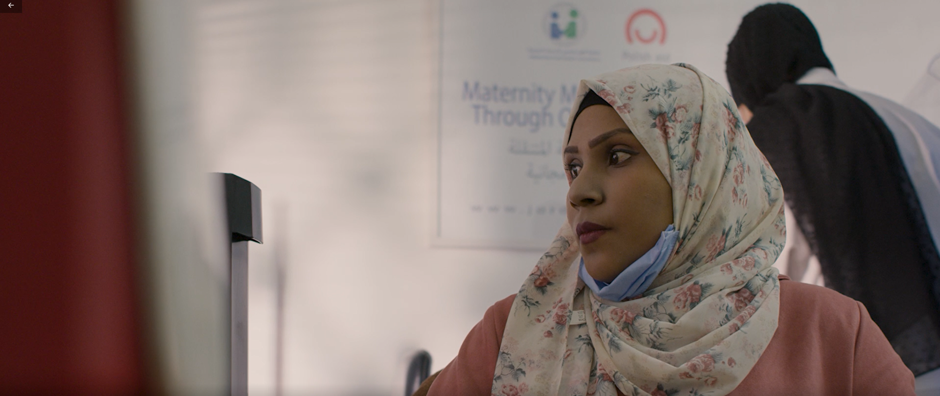 Kobieta w hidżabie we wzory w kwiaty w ujęciu do ramion patrzy w bok.