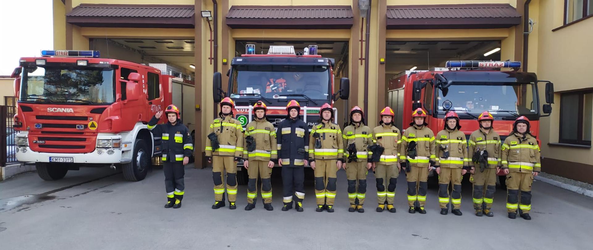 Zdjęcie przedstawia stojących przed samochodami strażaków w trakcie uroczystego apelu