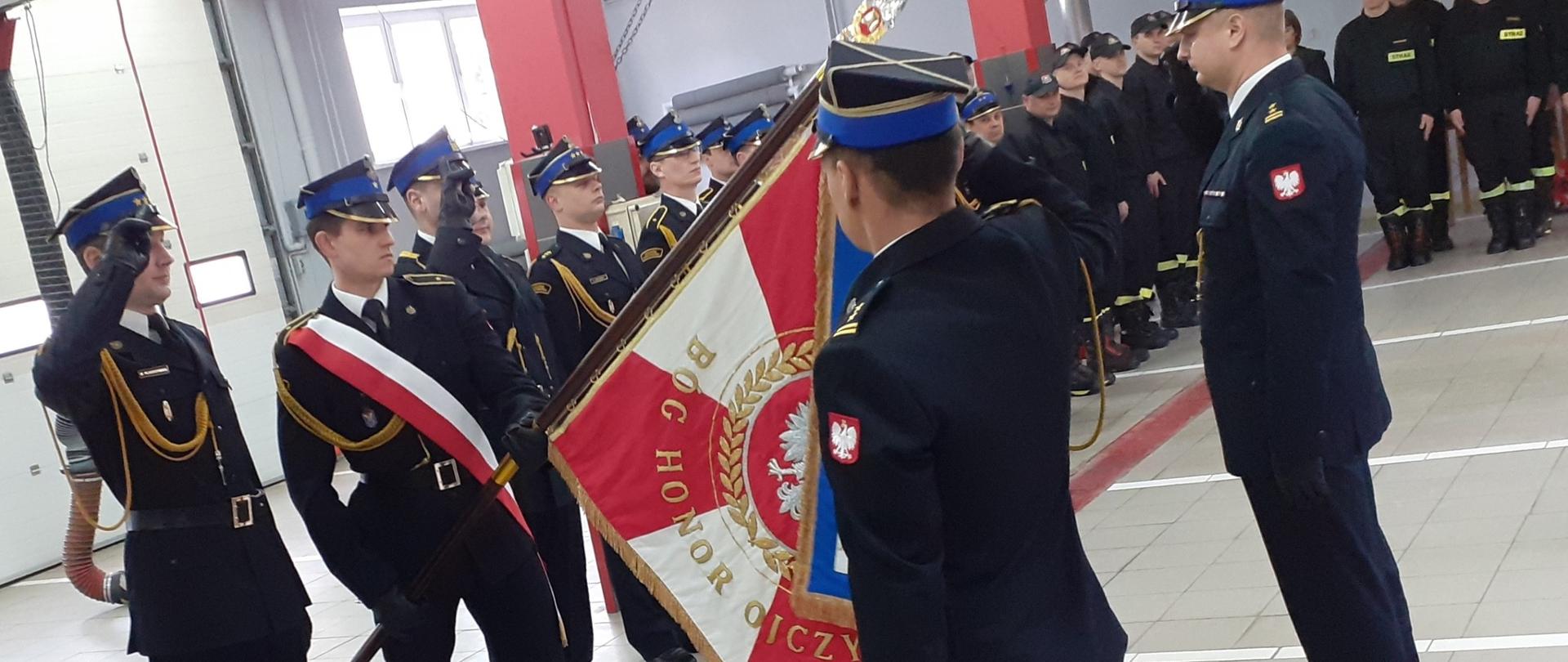 Poczet sztandarowy pochyla sztandar. Przed nim, z obu stron zdający i przyjmujący obowiązki, w mundurach galowych.