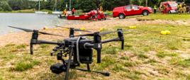 Dron przygotowany do startu, strażacy wodują łódź ratowniczą.