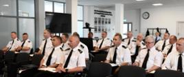 Funkcjonariusze Państwowej Straży Pożarnej w umundurowaniu wyjściowym siedzą na krzesłach.