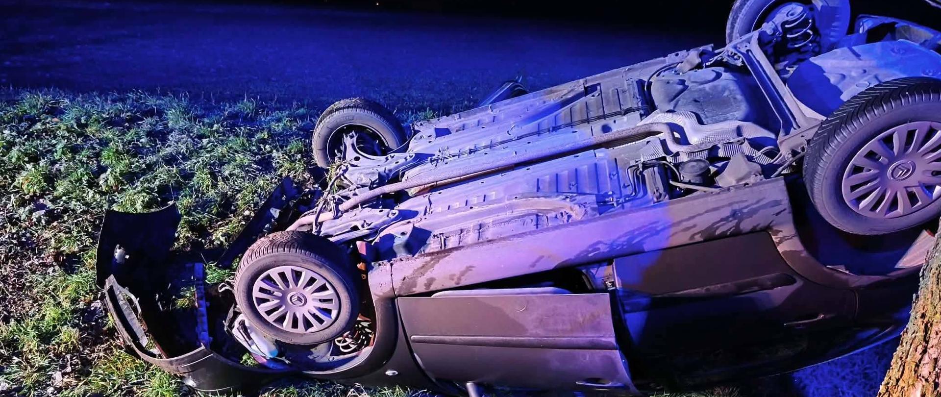 Samochód po dachowaniu w rowie przy drzewie, ciemno