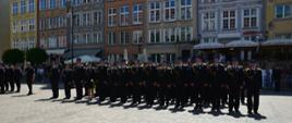 Strażacy w mundurach galowych stoją w rzędzie po wręczeniu odznaczeń.