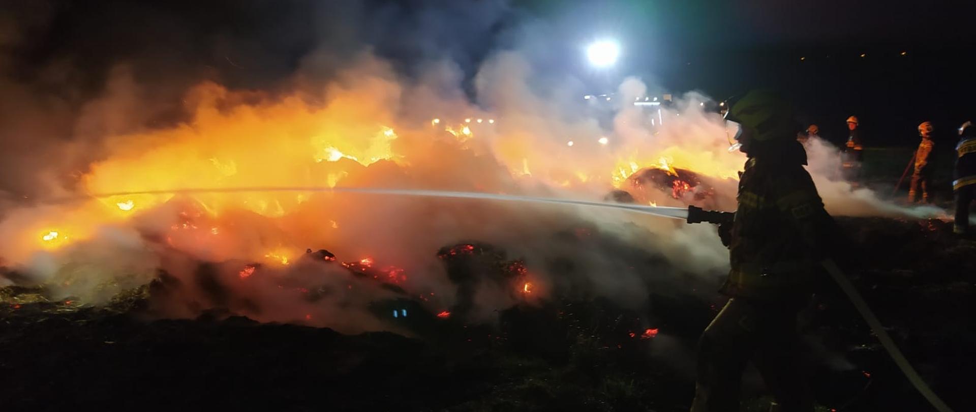 Na zdjęciu strażak gasi woda palącą się słomę