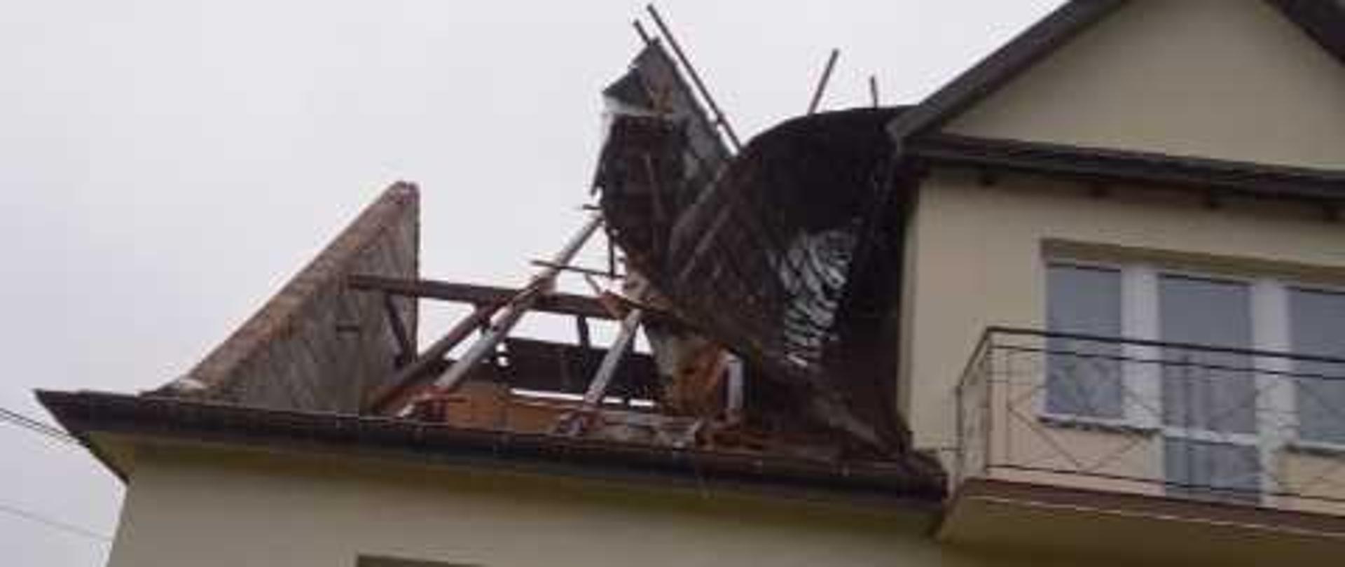 Zdjęcie przedstawia uszkodzenia części dachowej na budynku mieszkalnym powstałe w wyniku silnego wiatru.