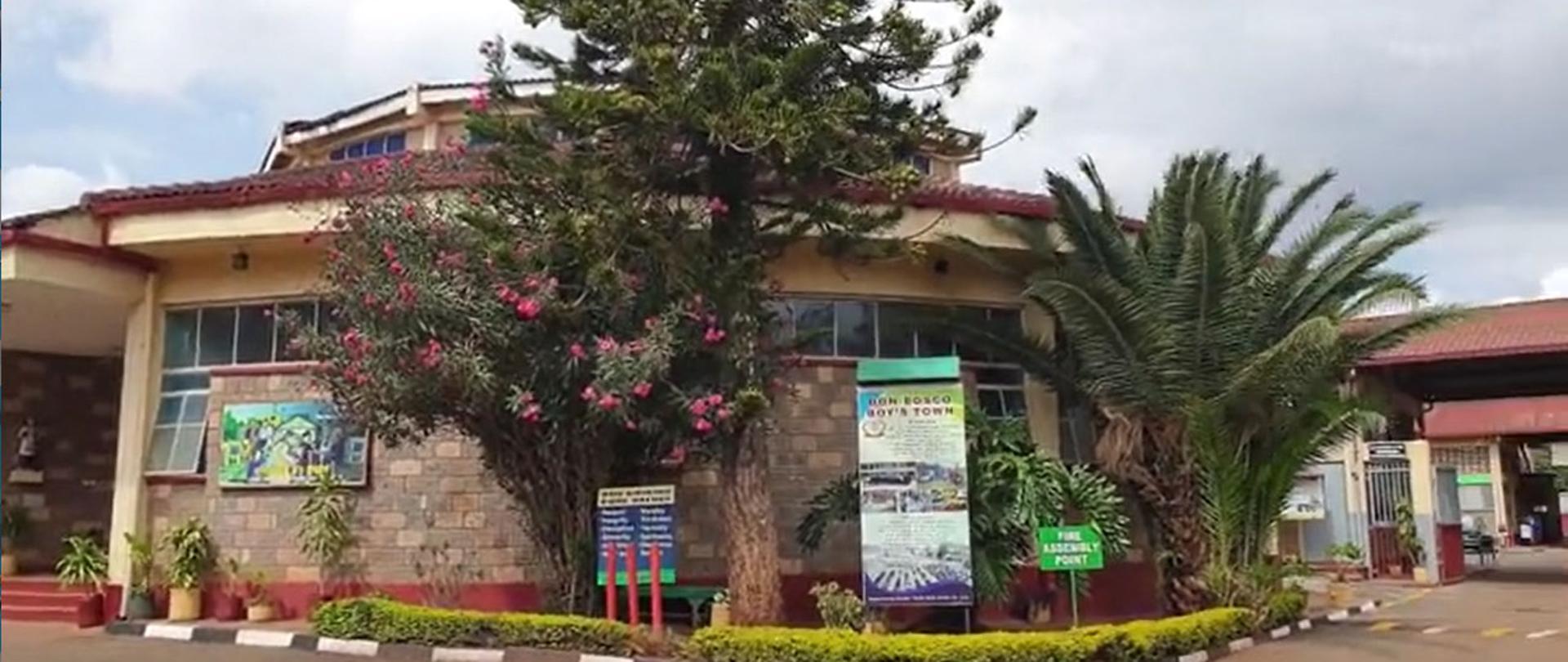 przed budynkiem bujna roślinność wraz z plakatami 