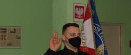 Zdjęcie przedstawia moment ślubowania strażaka Grzegorza Talkowskiego. Strażak Grzegorz Talkowski stoi obok sztandaru Komendy.