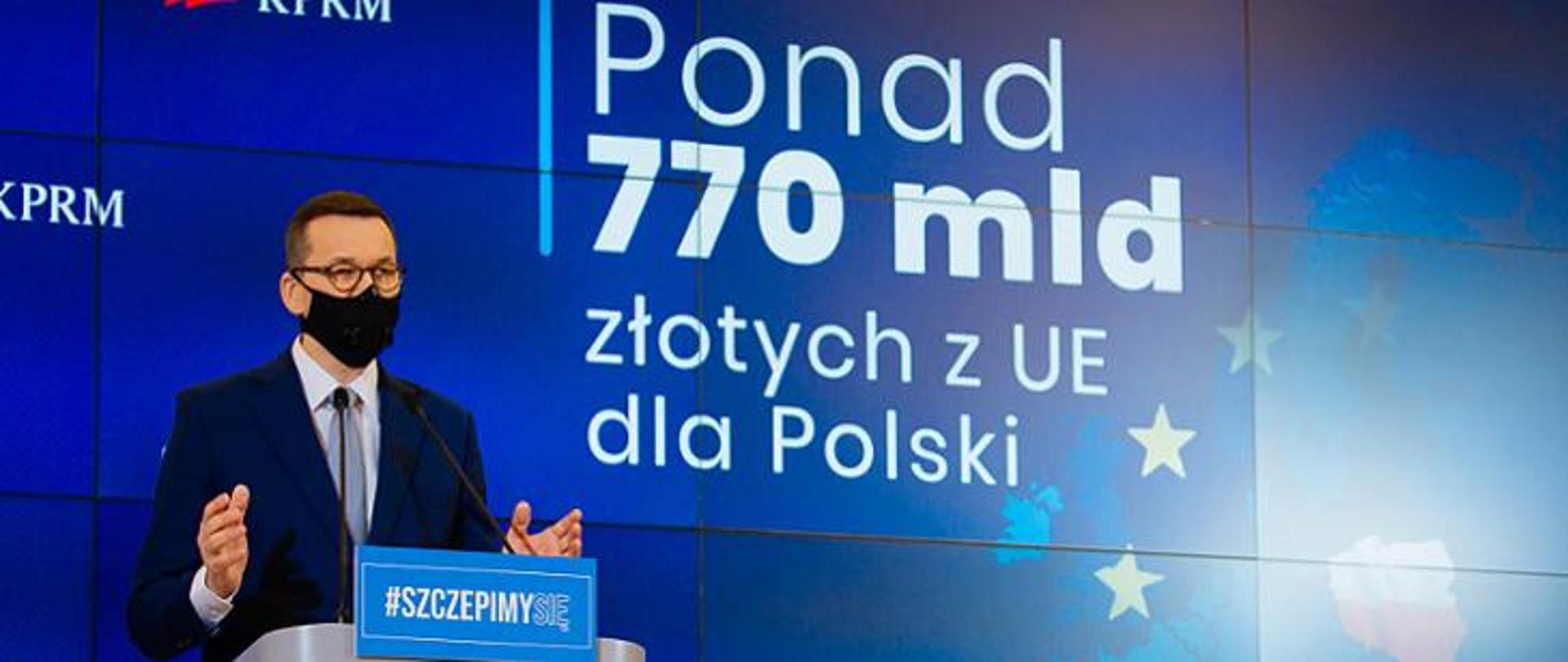 Premier Mateusz Morawiecki, w tle baner z napisem: Ponad 770 mld złotych z UE dla Polski