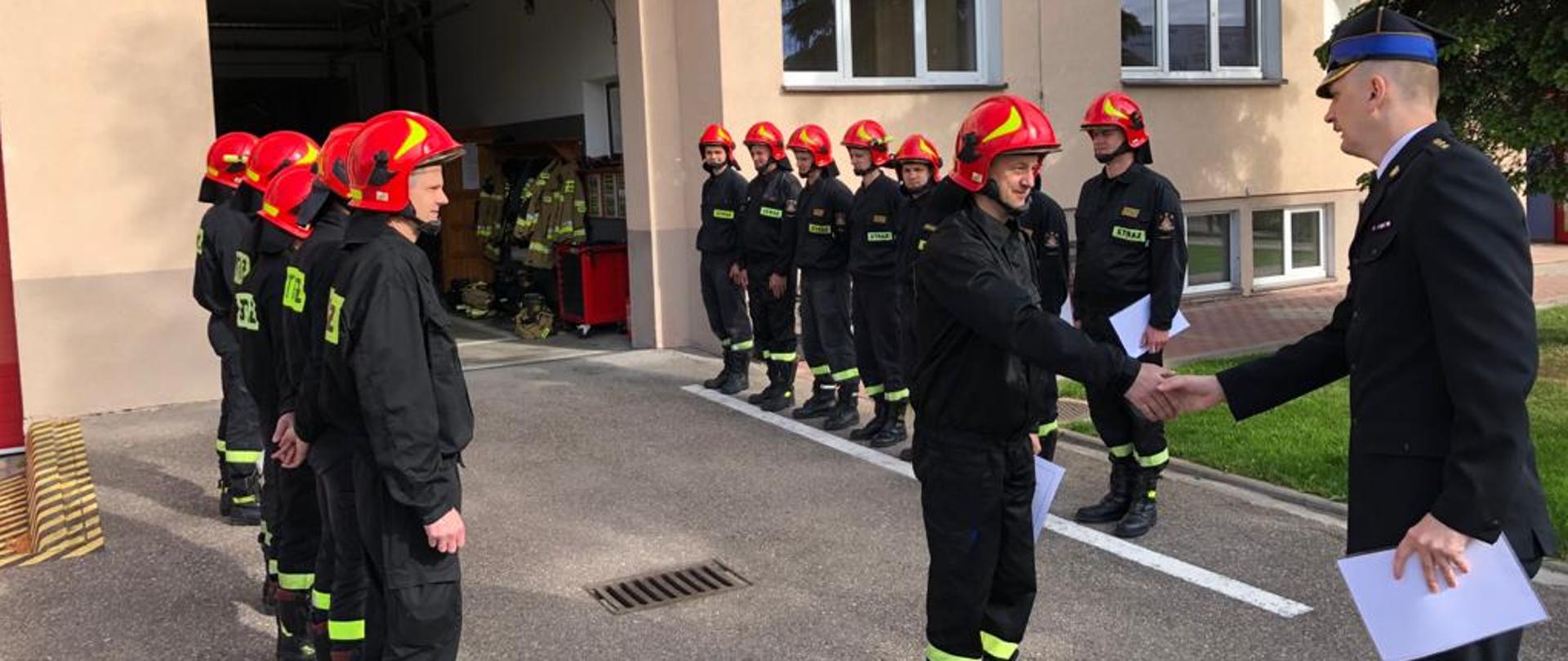 Zastępca Komendanta Powiatowego PSP w Ostródzie st. kpt. Rafał Napiórkowski wręczający decyzje o awansach na wyższe stanowiska służbowe za wzorowe wykonywanie obowiązków służbowych strażakom w JRG Morąg