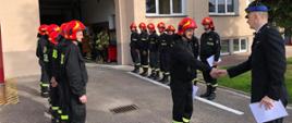 Zastępca Komendanta Powiatowego PSP w Ostródzie st. kpt. Rafał Napiórkowski wręczający decyzje o awansach na wyższe stanowiska służbowe za wzorowe wykonywanie obowiązków służbowych strażakom w JRG Morąg