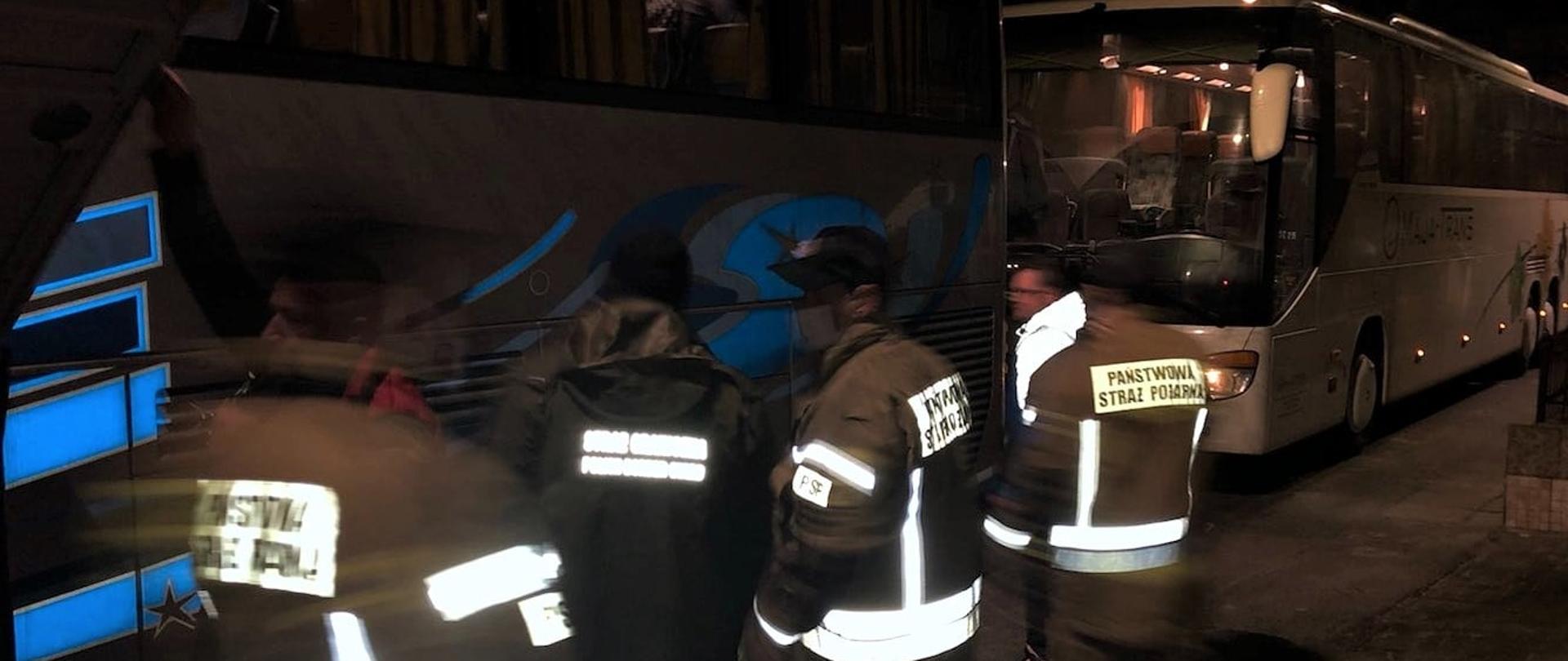 Zdjęcie przedstawia strażaków oraz autobusy przywożące dzieci z Ukrainy.