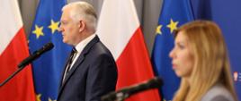 Wicepremier i minister rozwoju, pracy i technologii Jarosław Gowin na konferencji prasowej, po jego prawej stronie wiceminister rozwoju, pracy i technologii Anna Kornecka, w tle flagi Polski i UE

