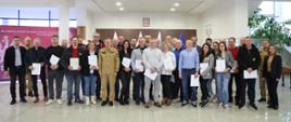 Pamiątkowe zdjęcie grupowe uczestników szkolenia inspektorów ochrony przeciwpożarowej (30 osób) w towarzystwie Zastępcy Komendanta Centralnej Szkoły PSP, kobiety oraz dwóch funkcjonariuszy CS PSP
