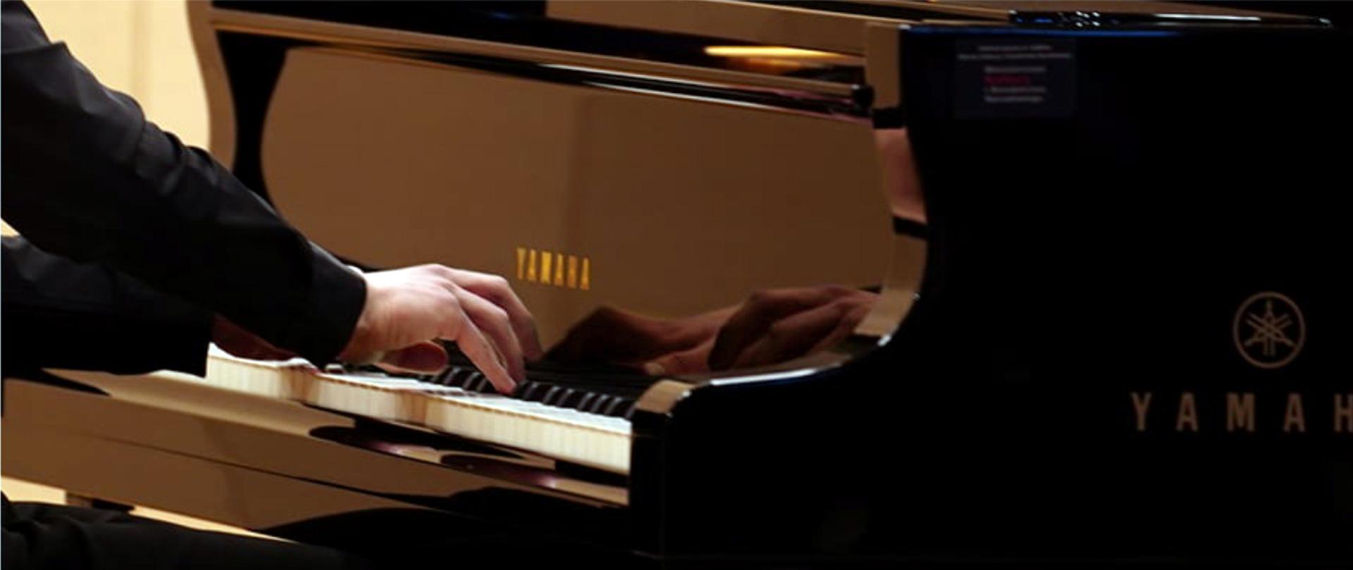 Zdjęcie przedstawia ręce pianisty grającego na fortepianie