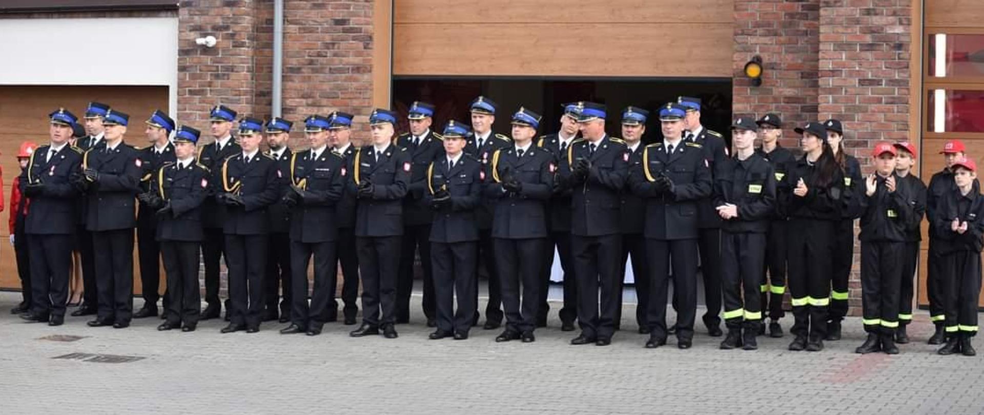 Pododdział Funkcjonariuszy Komendy Powiatowej PSP w Pucku. Wszyscy funkcjonariusze są ubrani w mundury galowe ze złotymi sznurami na prawym ramieniu oraz rogatywką na głowie.