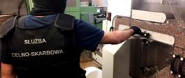 Funkcjonariusz KAS przy jednej z maszyn do produkcji papierosów.