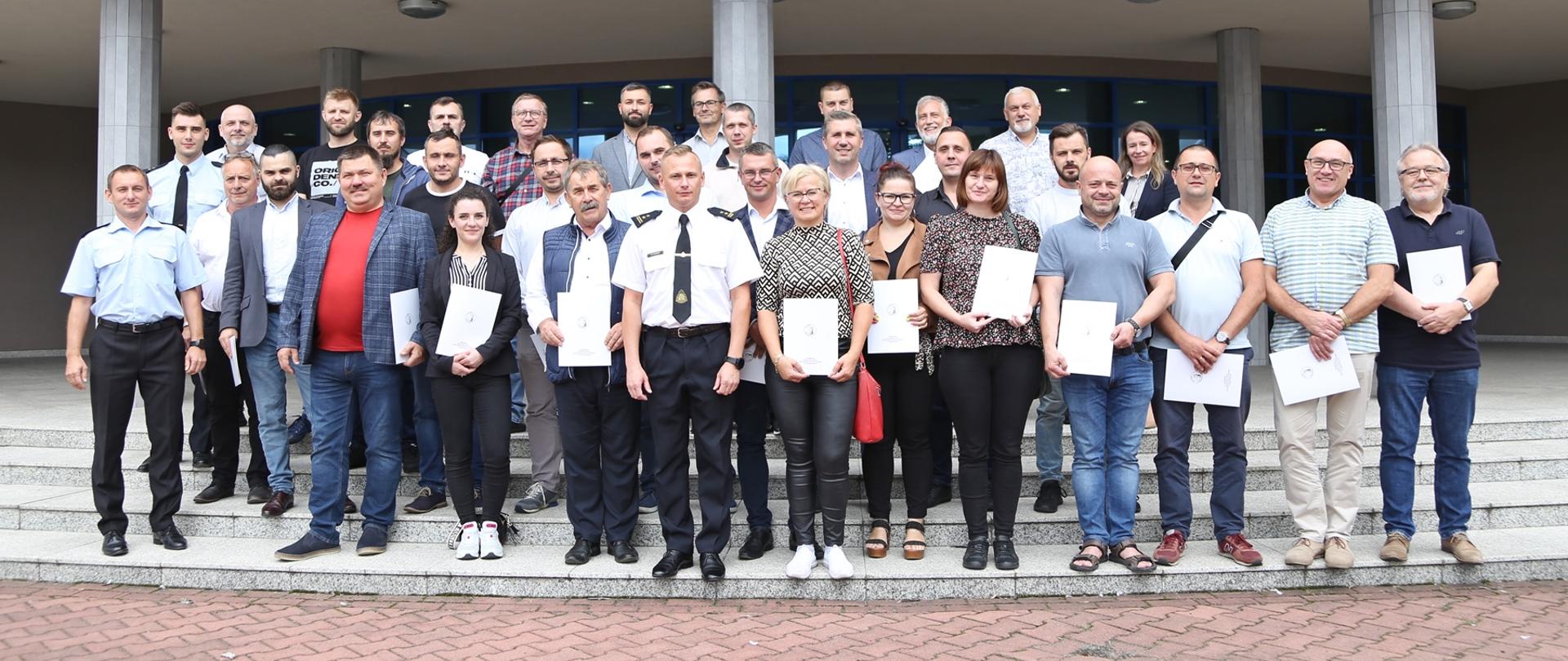 Grupowe zdjęcie uczestników szkolenia w towarzystwie Zastępcy Komendanta Centralnej Szkoły PSP oraz dwóch pracowników CS PSP