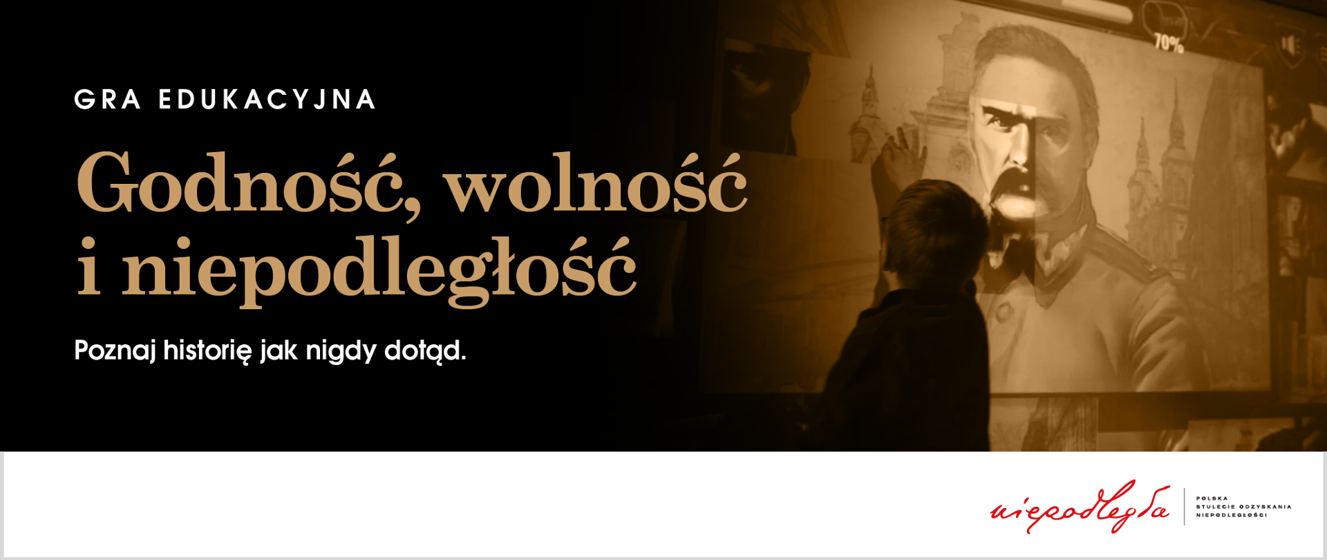 Chłopiec gra w grę edukacyjną i układa na ekranie postać Józefa Piłsudskiego. Obok tekst: Gra edukacyjna – Godność, wolność i niepodległość. Poznaj historię jak nigdy dotąd.