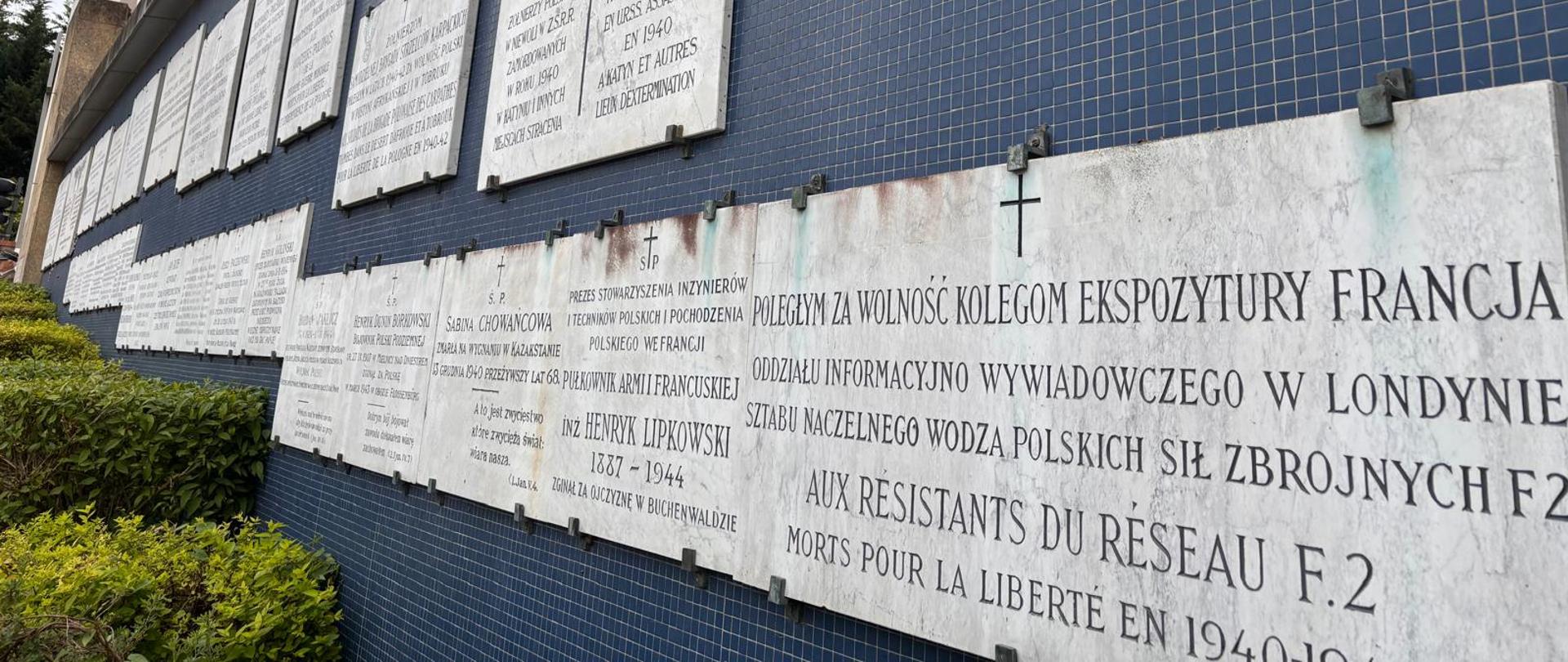 Zdjęcie muru z przymocowanymi do niego kamiennymi tablicami upamiętniającymi poległych.
