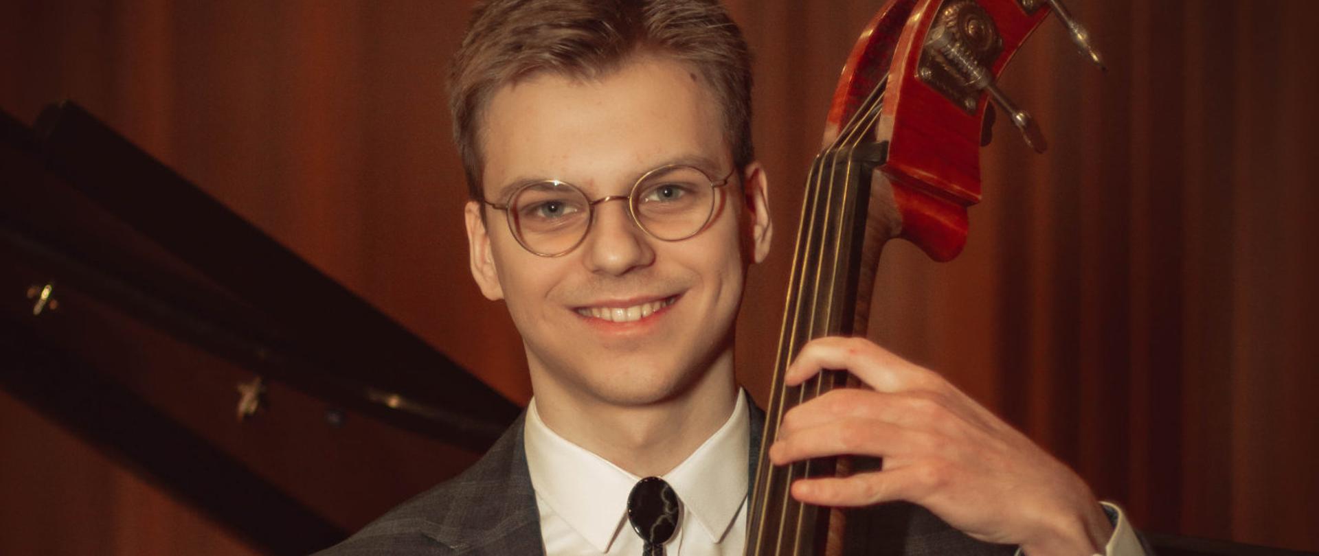 Plakat recitalu dyplomowego Franciszka Jasińskiego. Przedstawia zdjęcie wykonawcy recitalu z kontrabasem. Na ciemnym tle. Na plakacie białą czcionką napisany jest program recitalu, data, nazwisko wykonawcy oraz nauczyciela.