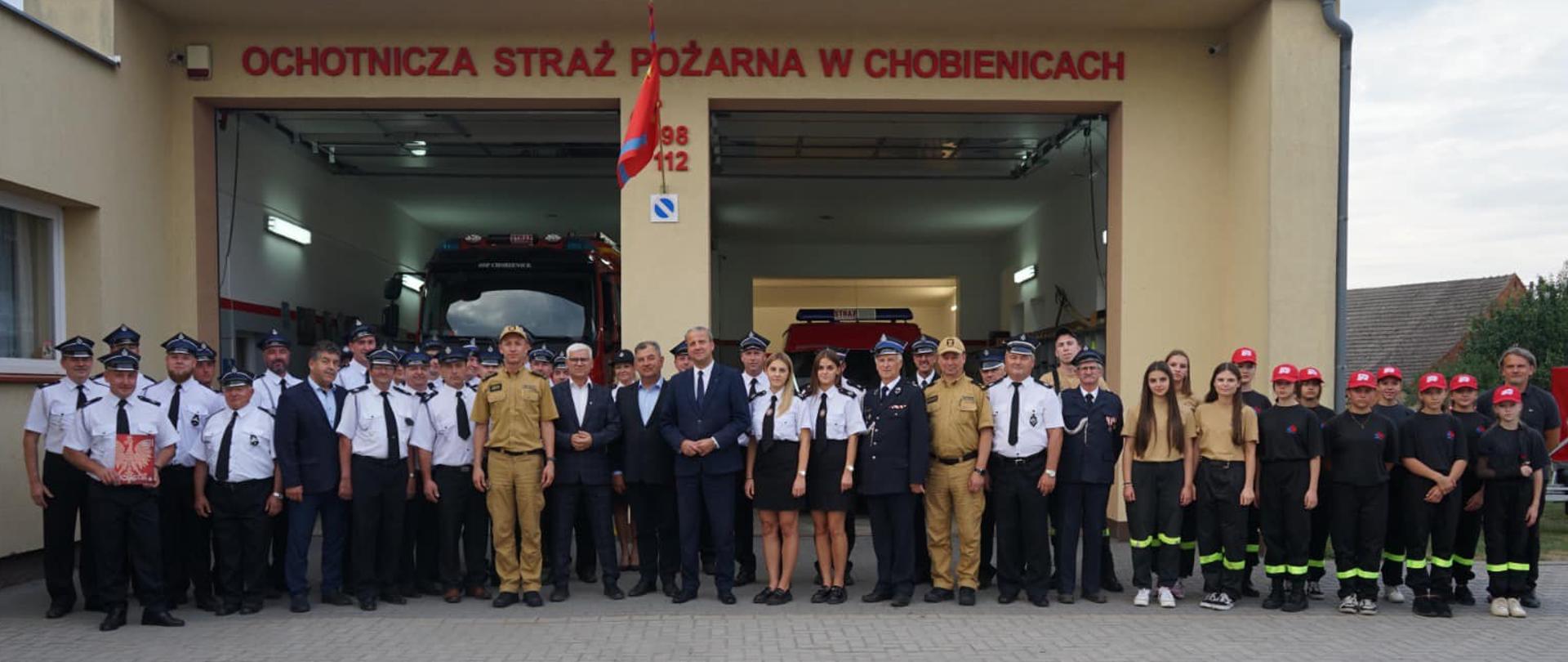 zdjęcie grupowe druhów osp i mdp, w tle otwarte garaże reminy 