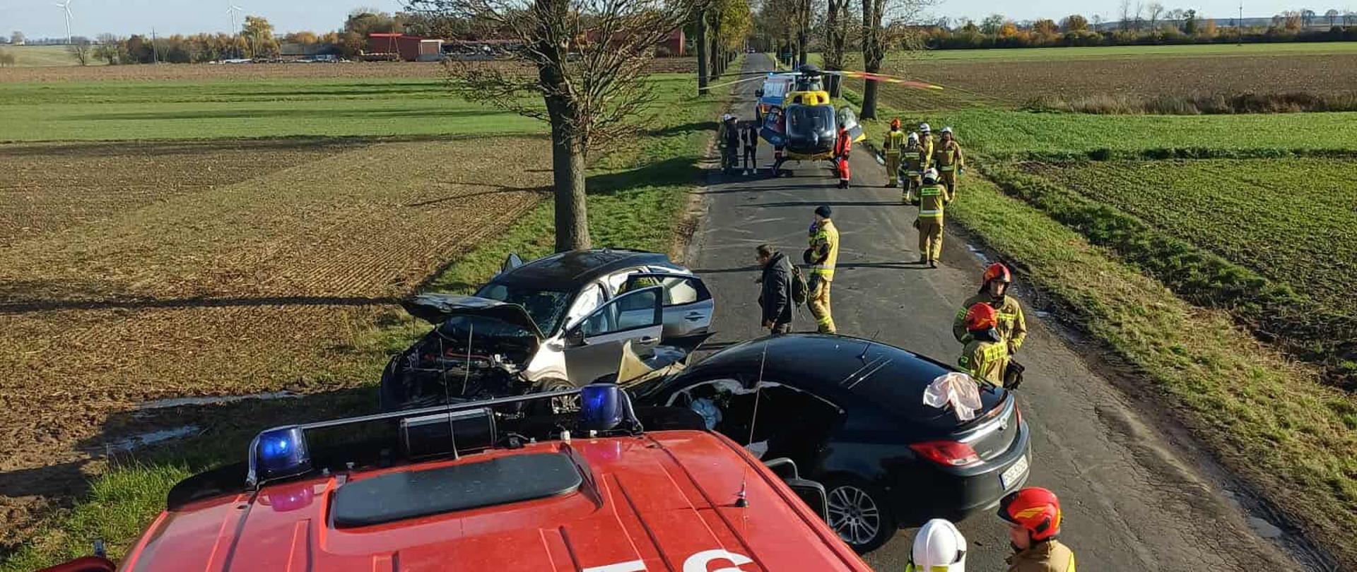 Zdjęcie z góry. Widać uszkodzone pojazdy, strażaków oraz w tle śmigłowiec.