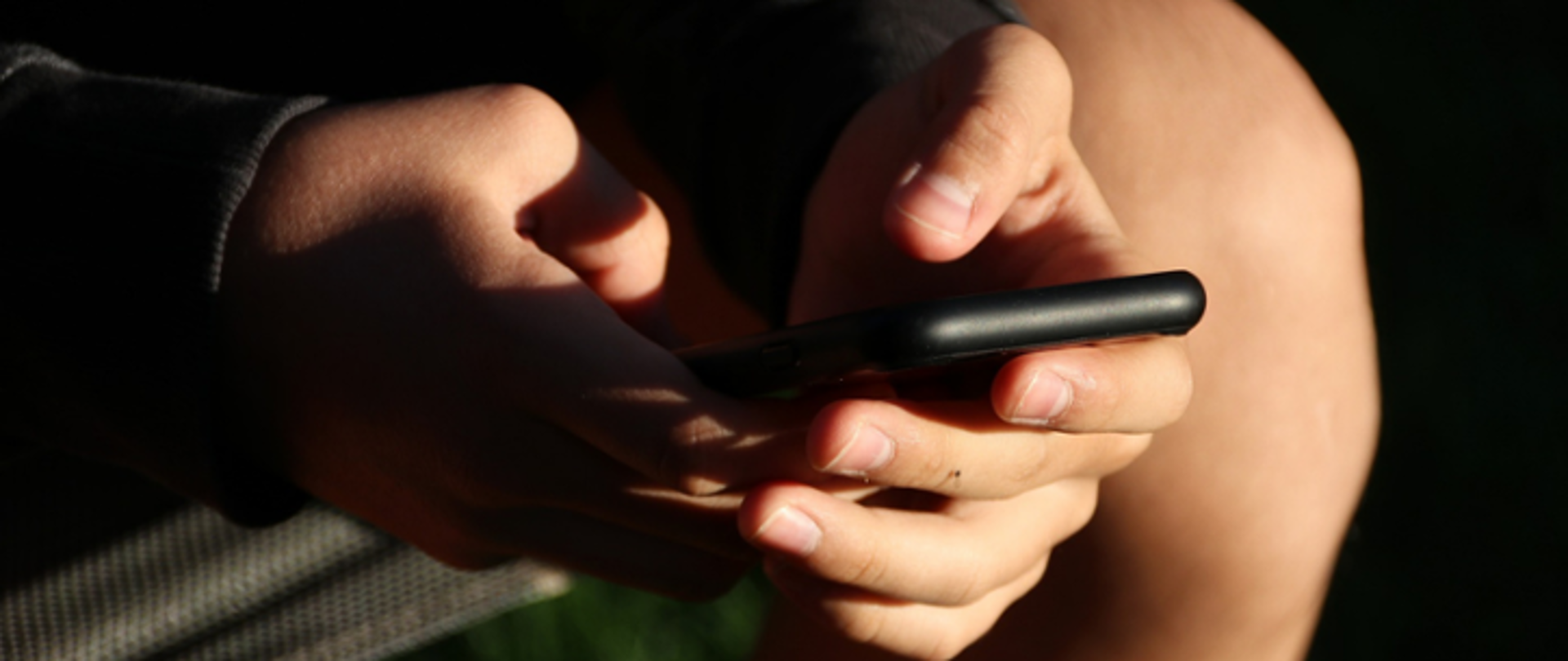 Na zdjęciu znajdują się dłonie mężczyzny trzymającego telefon.