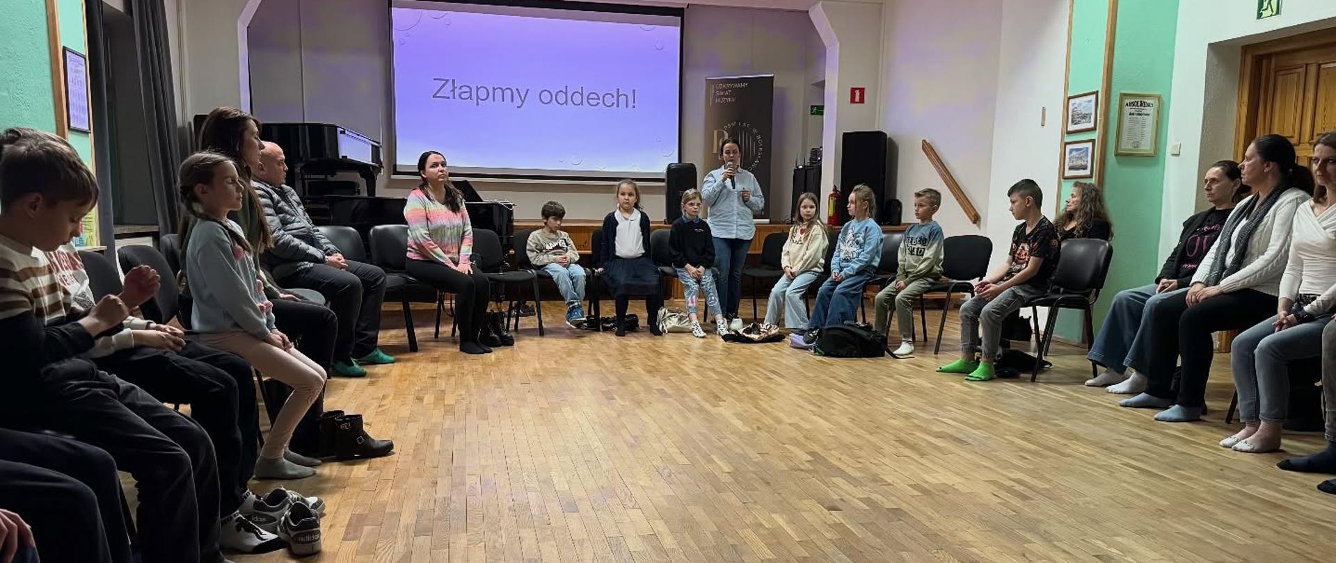 Zdjęcie przedstawiające uczestników drugiej edycji warsztatów oddechowych przeprowadzonych przez Magdalenę Falewicz-Wesołowską - nauczyciela klasy klarnetu, które odbyły się 27 października 2025 roku w auli szkoły.