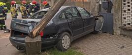 Na zdjęciu widoczny samochód osobowy (volkswagen passat), który uderzył w słup oraz bramę do posesji. 