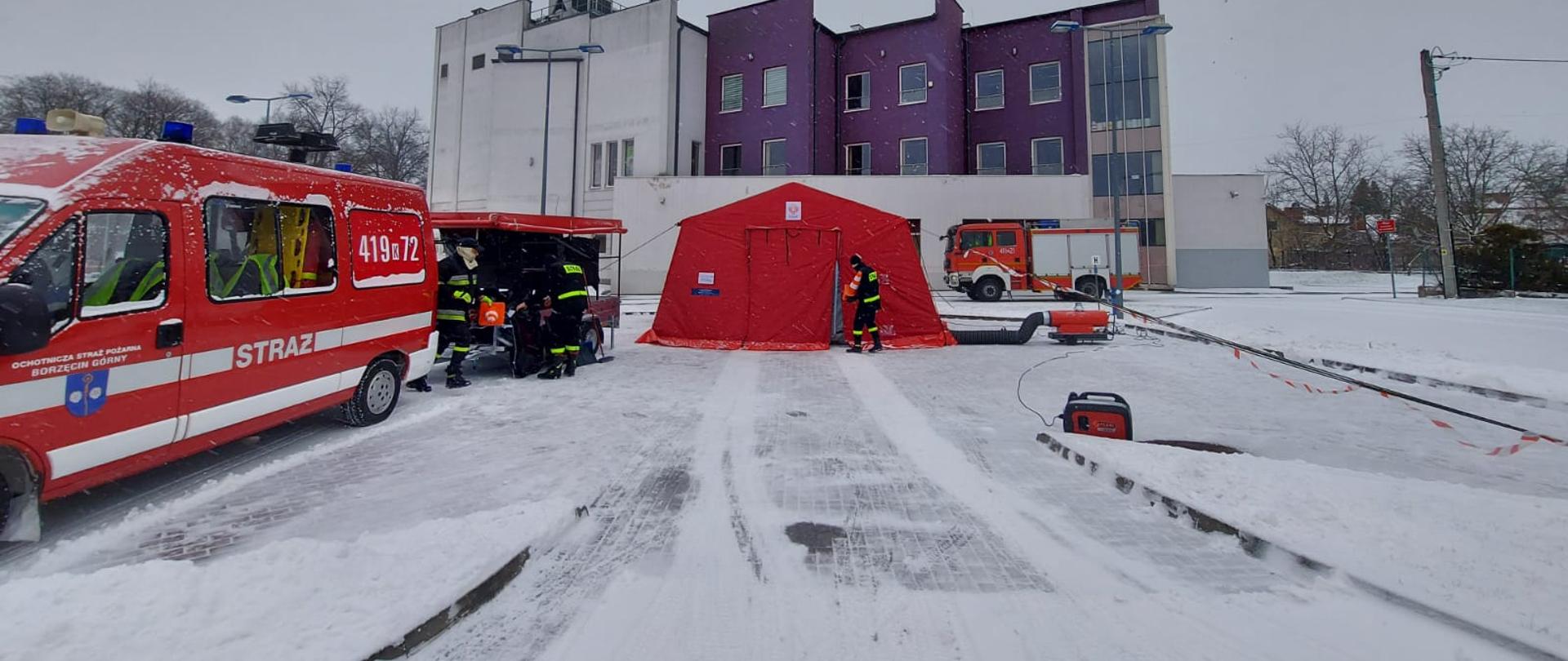 Na zdjęciu widoczni strażacy którzy tworzą punkt do pobierania wymazów