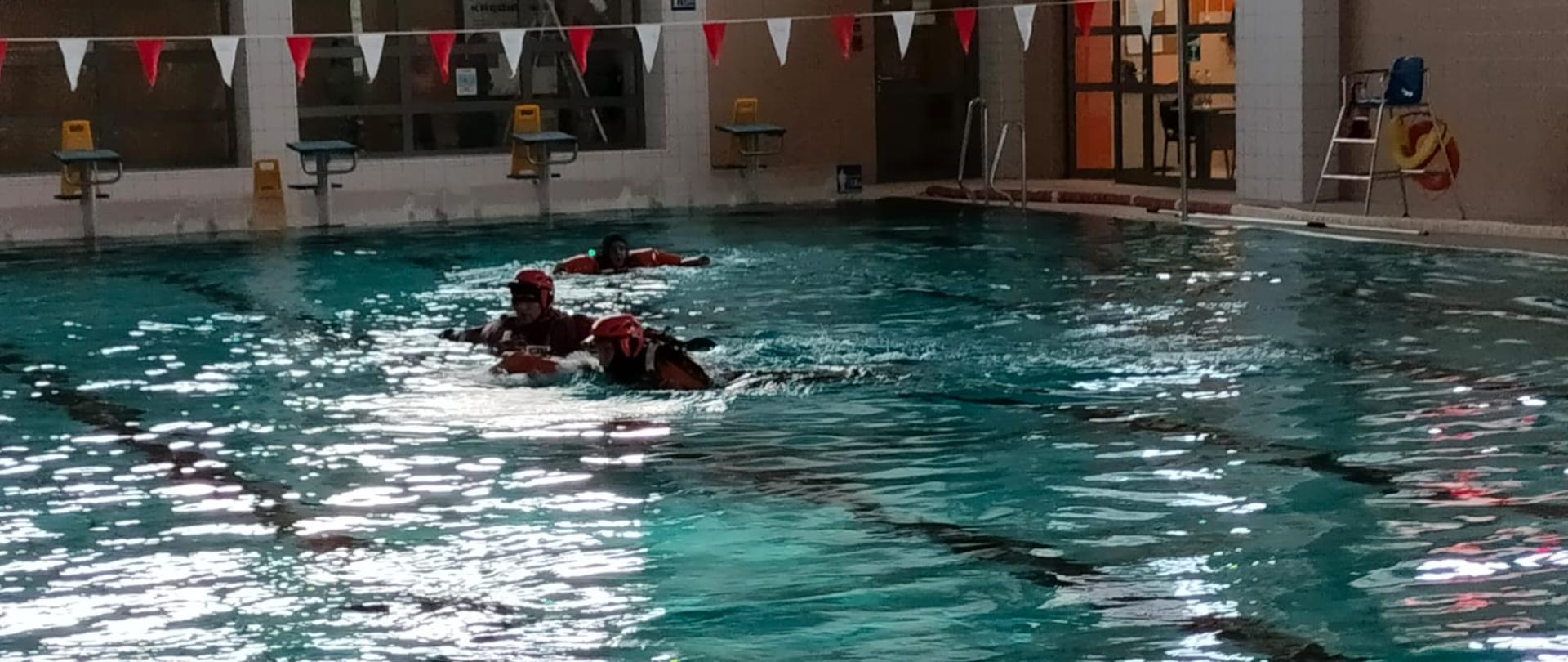 Zdjęcie przedstawia ćwiczących strażaków w basenie