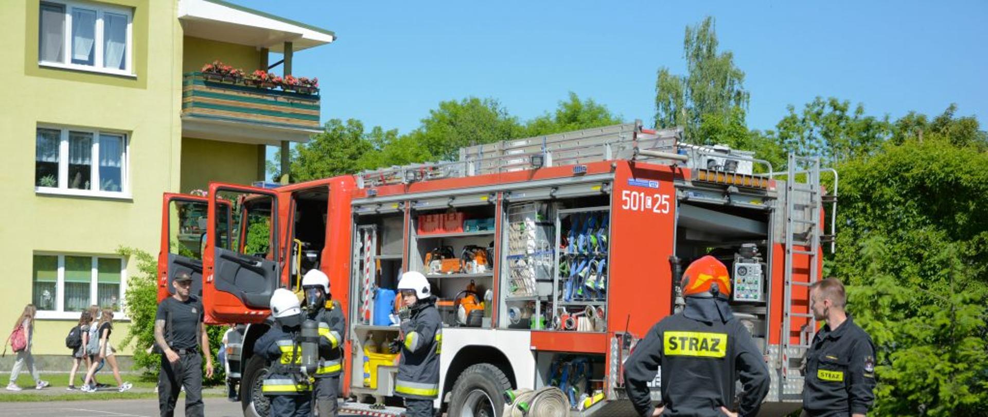 Zdjęcie przedstawia strażaków prezentujących młodzieży wóz strażacki SCANIA - GCBA 5/32/2,5.