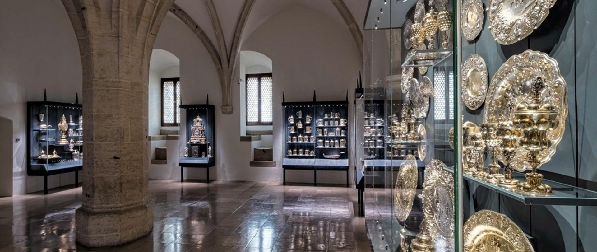 Widok na marmurową podłogę i złote naczynia w szklanej gablocie 