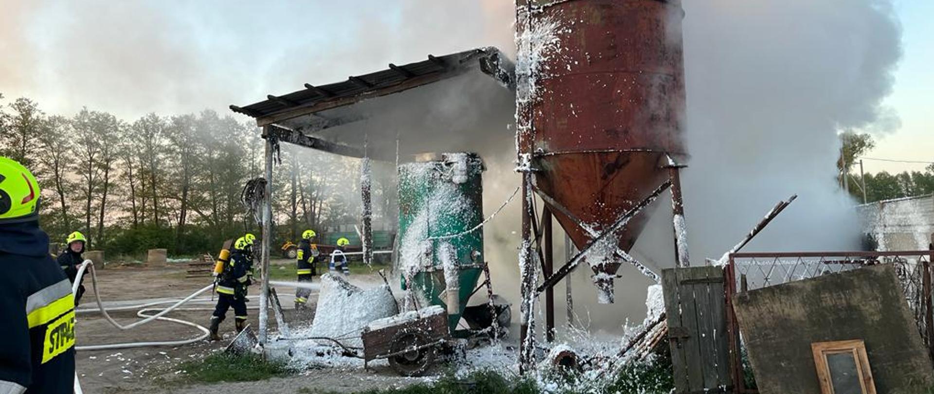 Kierujący działaniem ratowniczym nadzoruje akcję gaśniczą. Strażacy zabezpieczają teren działań oraz prowadzą działania gaśnicze z użyciem prądu piany ciężkiej. Bardzo dużo unoszącego się dymu.