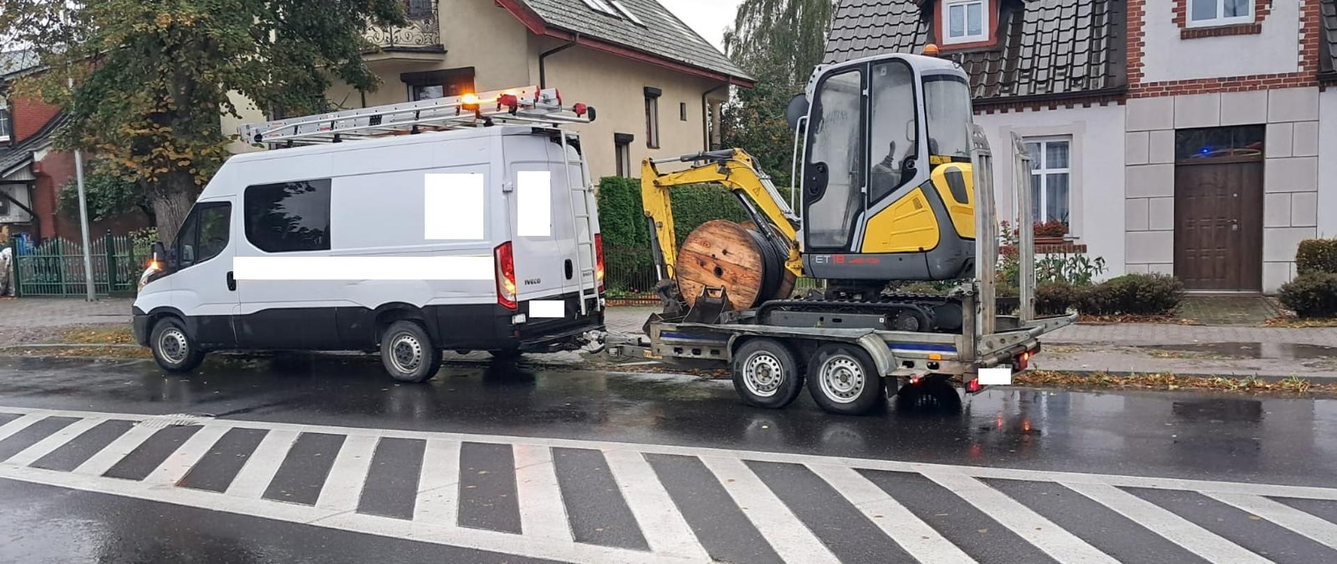 Samochód z koparką na przyczepie na skrzyżowaniu