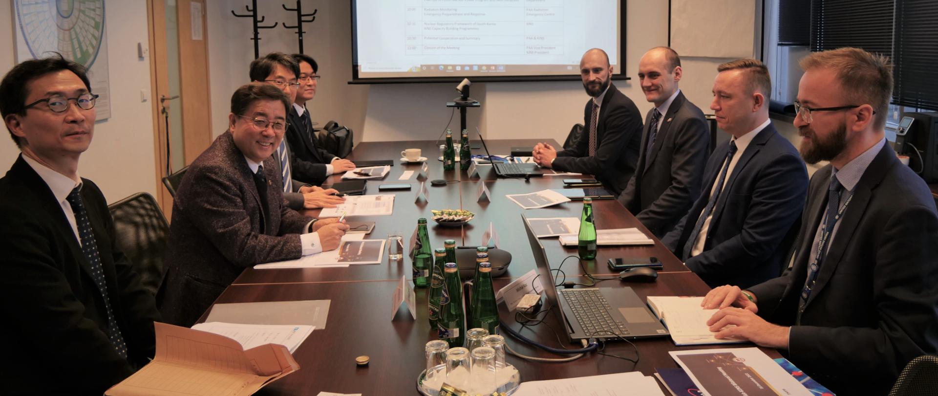 Spotkanie Państwowej Agencji Atomistyki i Koreańskiego Instytutu Bezpieczeństwa Jądrowego w siedzibie PAA - obie delegacji siedzą przy stole.