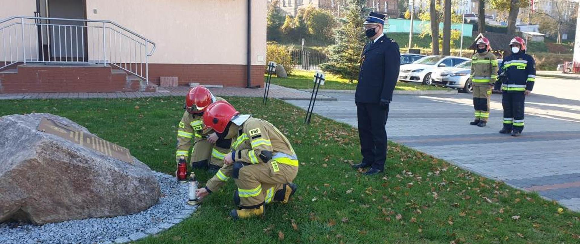 Strażacy ustawiający znicze na cześć zmarłych strażaków