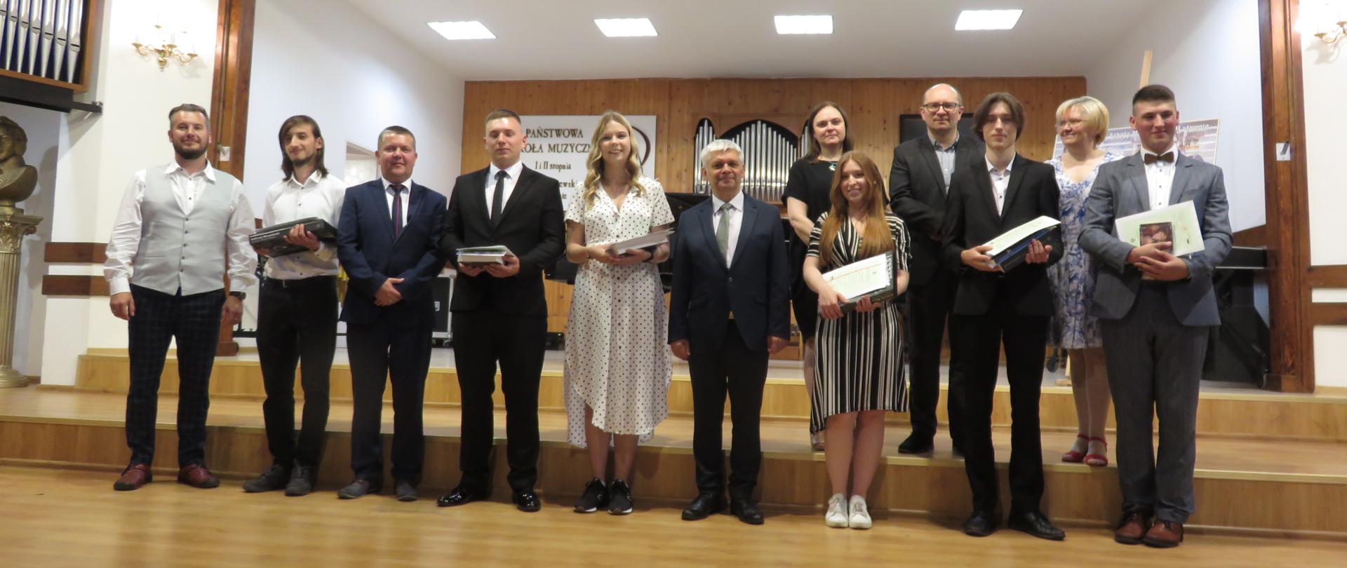 Absolwenci PSM II st 2022 stoją na scenie wraz z pedagogami i panem Dyrektorem