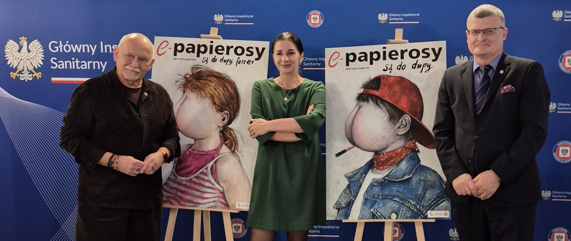 Dwaj mężczyźni i kobieta w środku stoją prezentując dwa plakaty na sztalugach