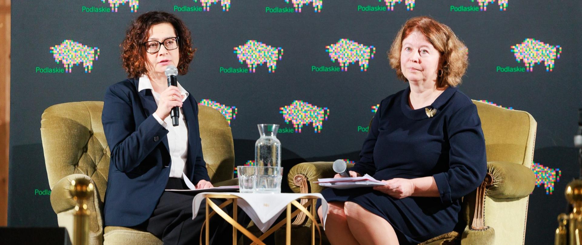 Przedstawicielki II US w Białymstoku podczas prelekcji, siedzą na fotelach, jedna mówi do mikrofonu