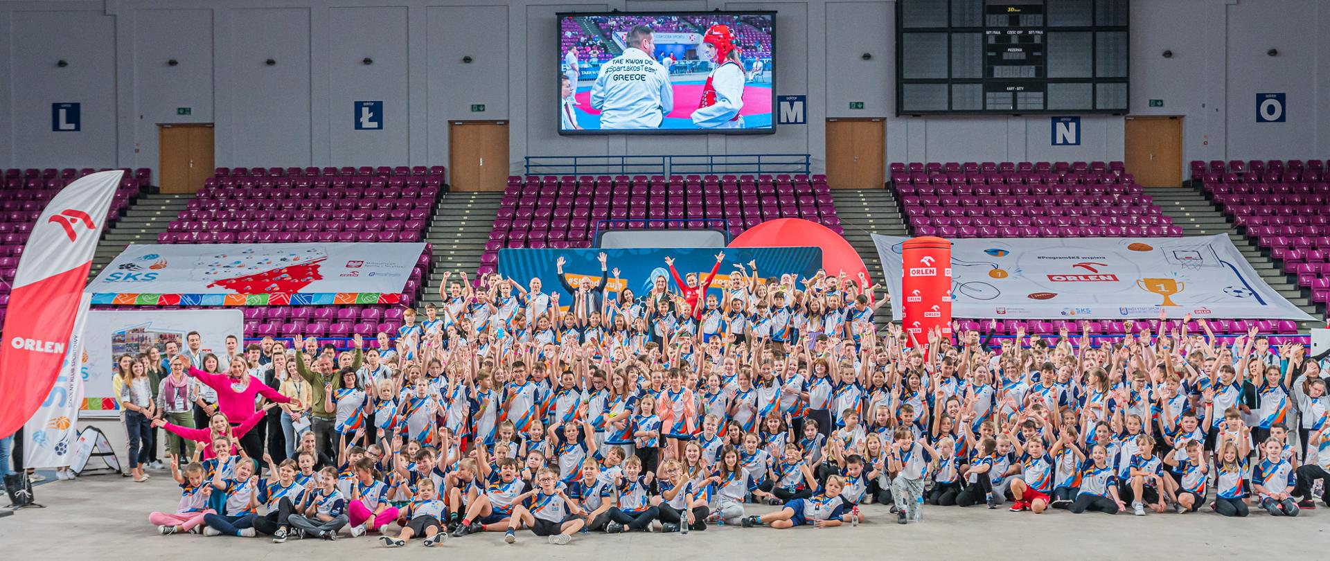 Ponad 272 000 uczniów w całej Polsce korzysta obecnie z bezpłatnych zajęć sportowych w ramach Programu Szkolny Klub Sportowy. Poprawa kondycji dzieci i młodzieży oraz promocja aktywności fizycznej to jedno z kluczowych zadań, jak stawia sobie Ministerstwo Sportu i Turystyki. Dzieci uczestniczące w Programie spotkały się na zajęciach na Torwarze. Na zdjęciu szczęśliwa grupa dzieci w hali Torwaru