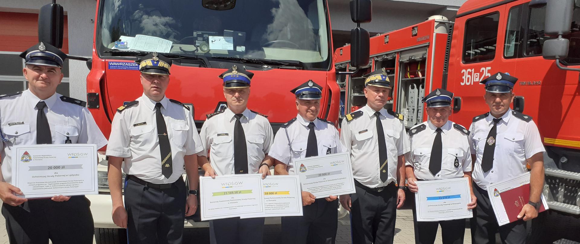 strażacy na tle samochodów p[ożarniczych