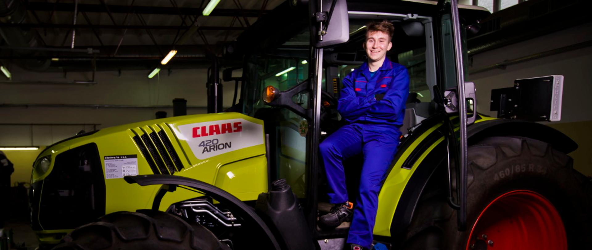 uczeń z technikum rolnictwa pozuje w ciągniku marki Claas