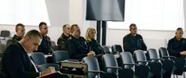 Strażacy oraz dyrektor Morskiej Służby Poszukiwania i Ratownictwa siedzą podczas spotkania zespołu. 