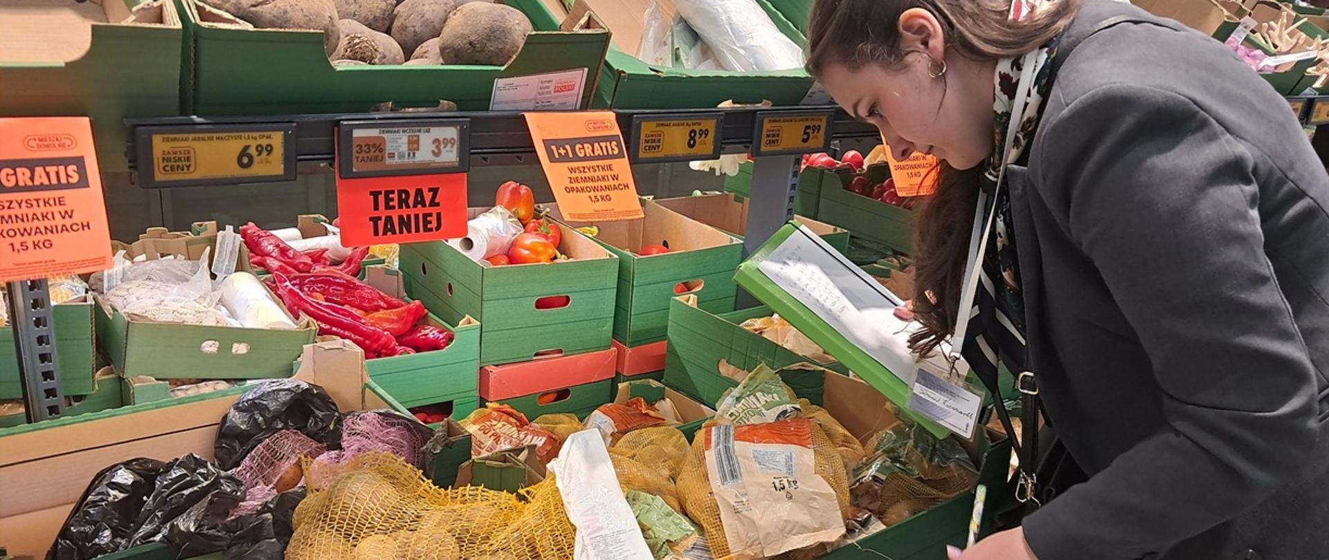 Skrzynki wypełnione ziemniakami ustawione na stoisku warzywnym.